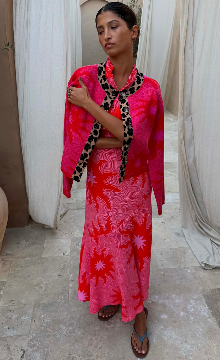 Woman wearing a bright pink floral dress with a leopard print scarf in an indoor setting.