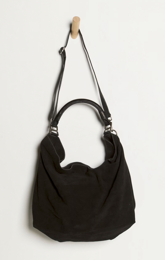 Black shoulder bag hanging on a wooden hook against a white background
