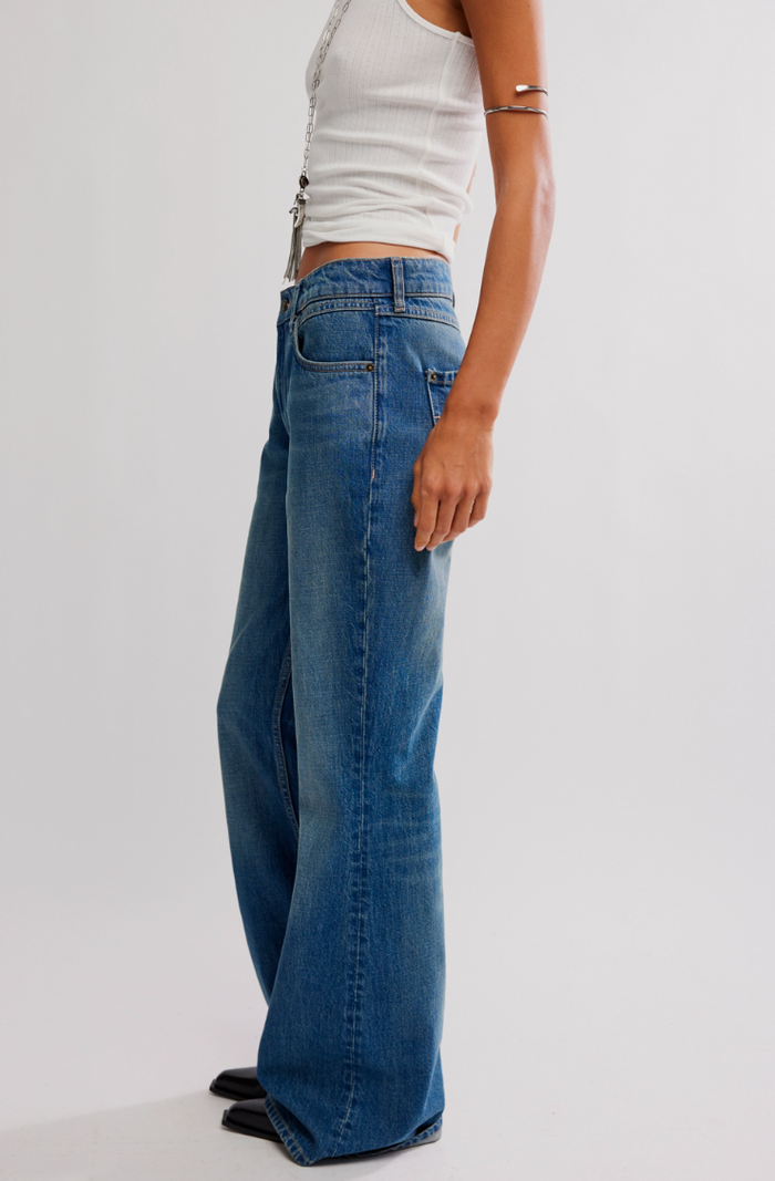 Person wearing blue jeans and a white top on a plain background