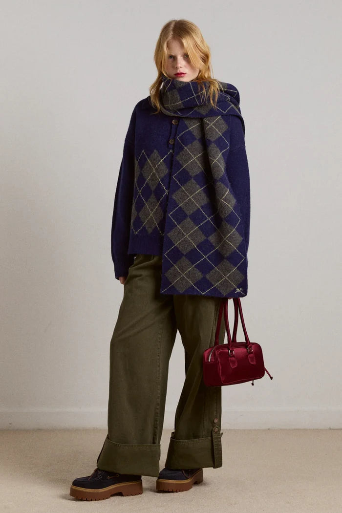 Woman wearing a blue argyle patterned coat with a red handbag on a plain background with Wylie Turn Up Jeans in khaki